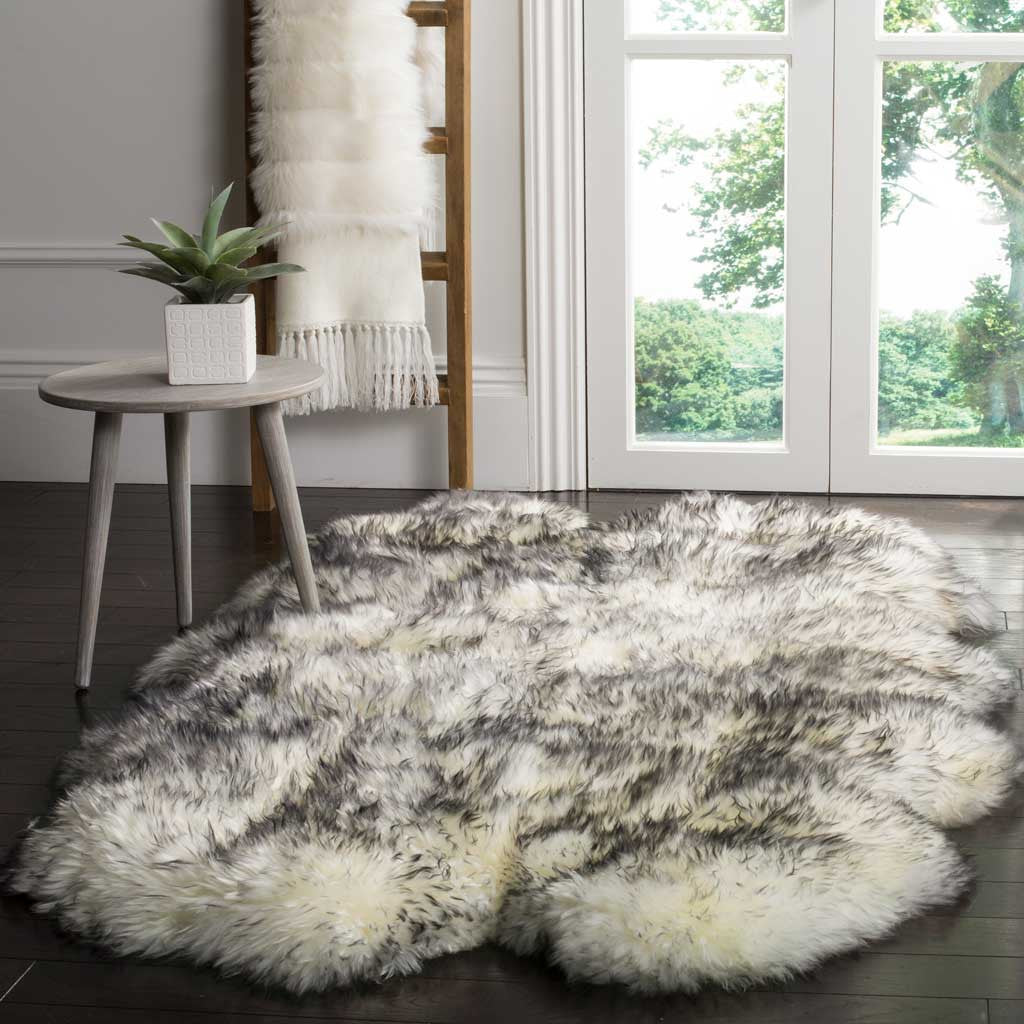 A spacious ivory-and-gray sheepskin warms dark flooring near a slim side table.