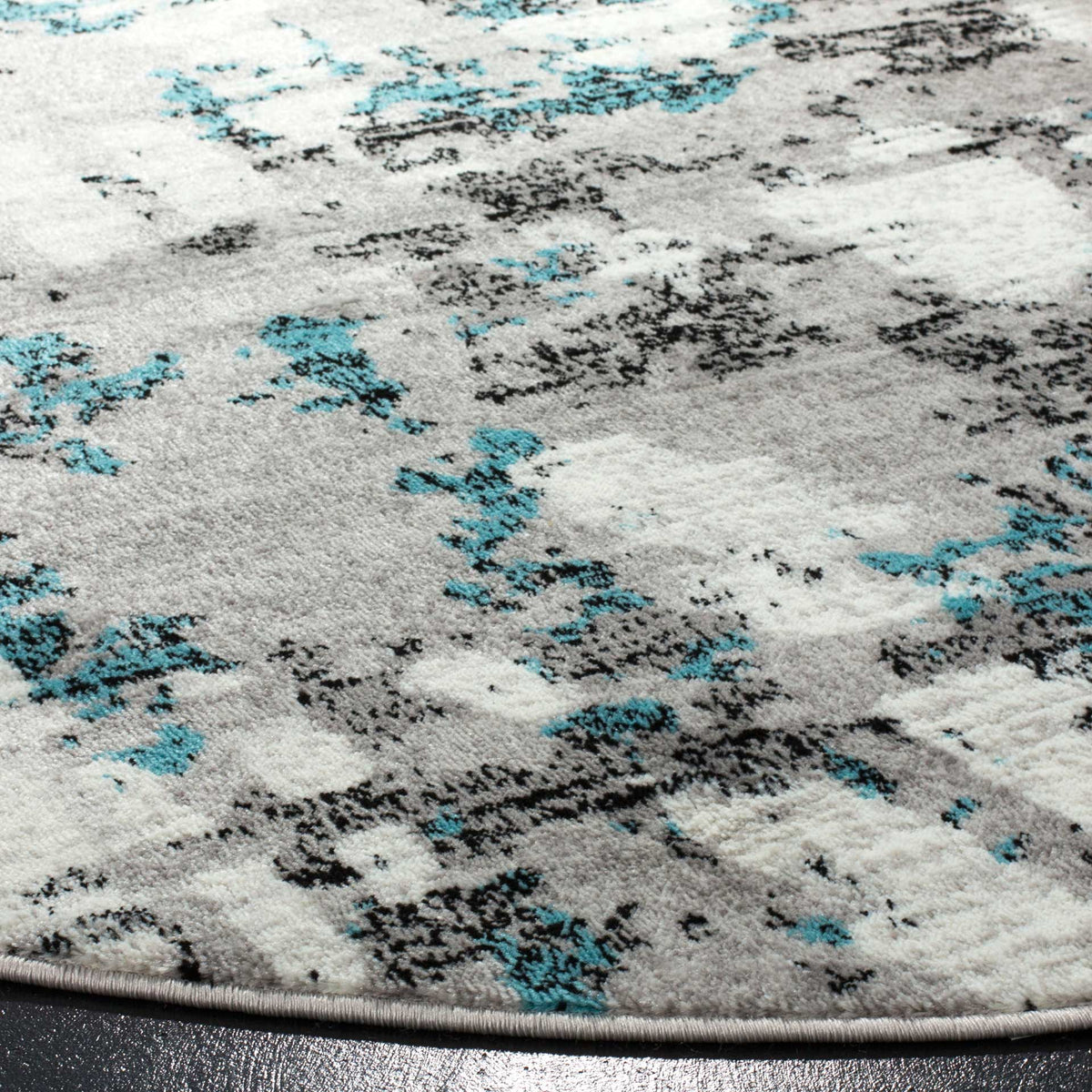 Turquoise and charcoal marks run through the textured gray pile above a neatly bound edge.