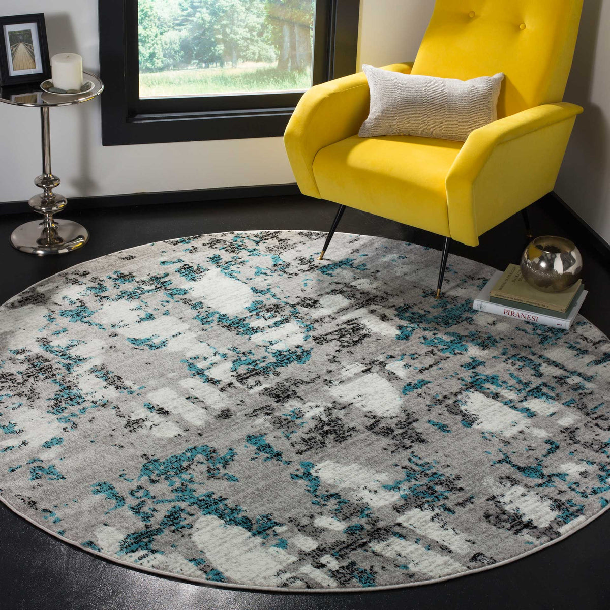 This round abstract rug layers turquoise-blue strokes over gray and ivory beneath a lounge chair.