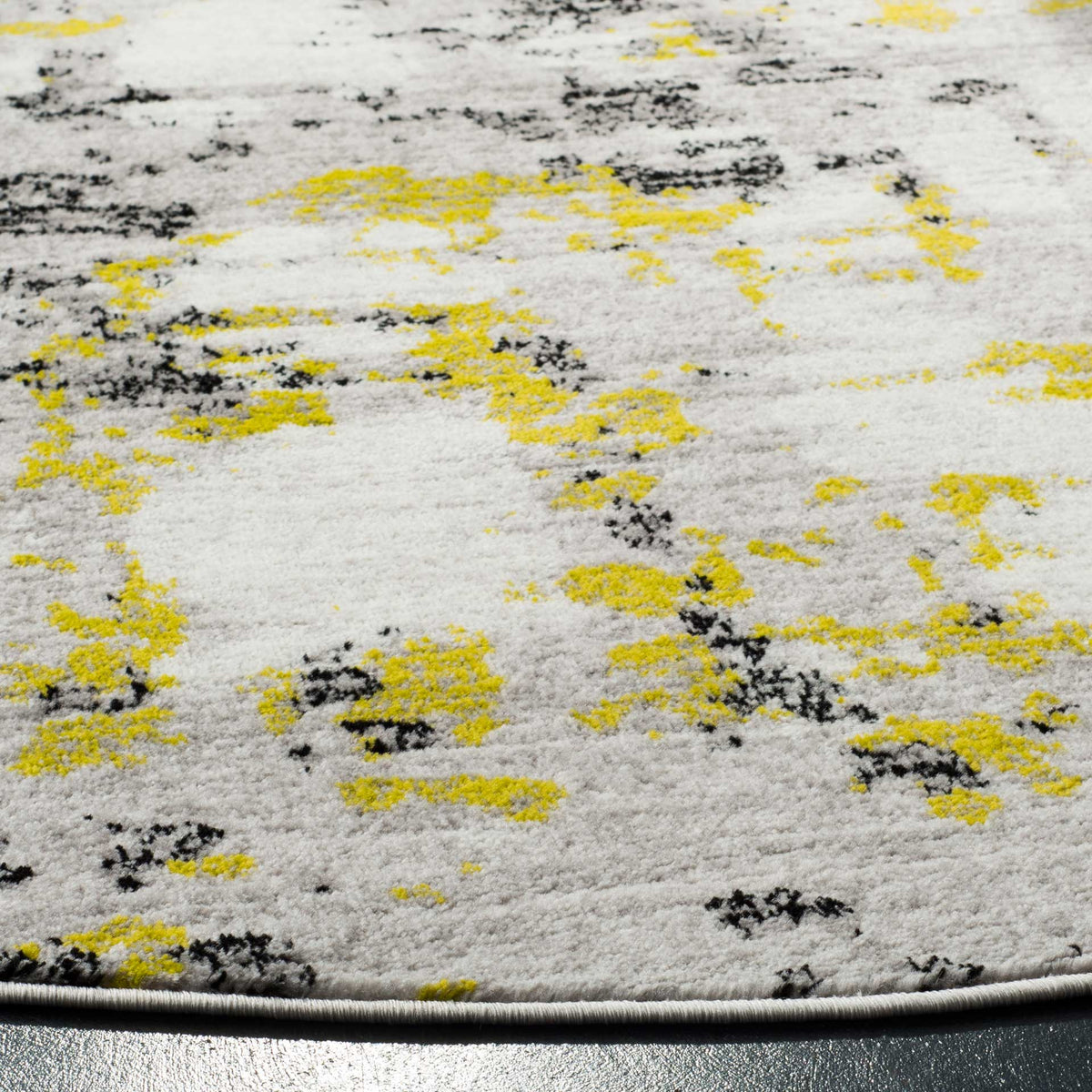 Yellow-green flecks and charcoal strokes punctuate the textured gray pile and curved bound edge.