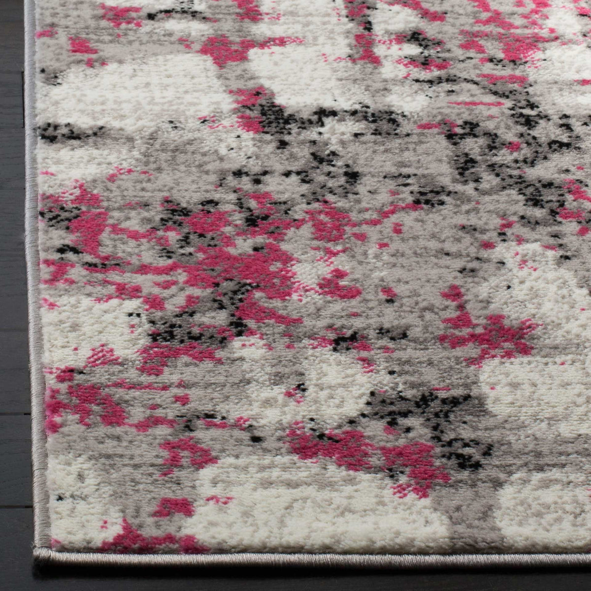 Pink splashes and charcoal flecks bring color to the textured pile and neatly bound corner