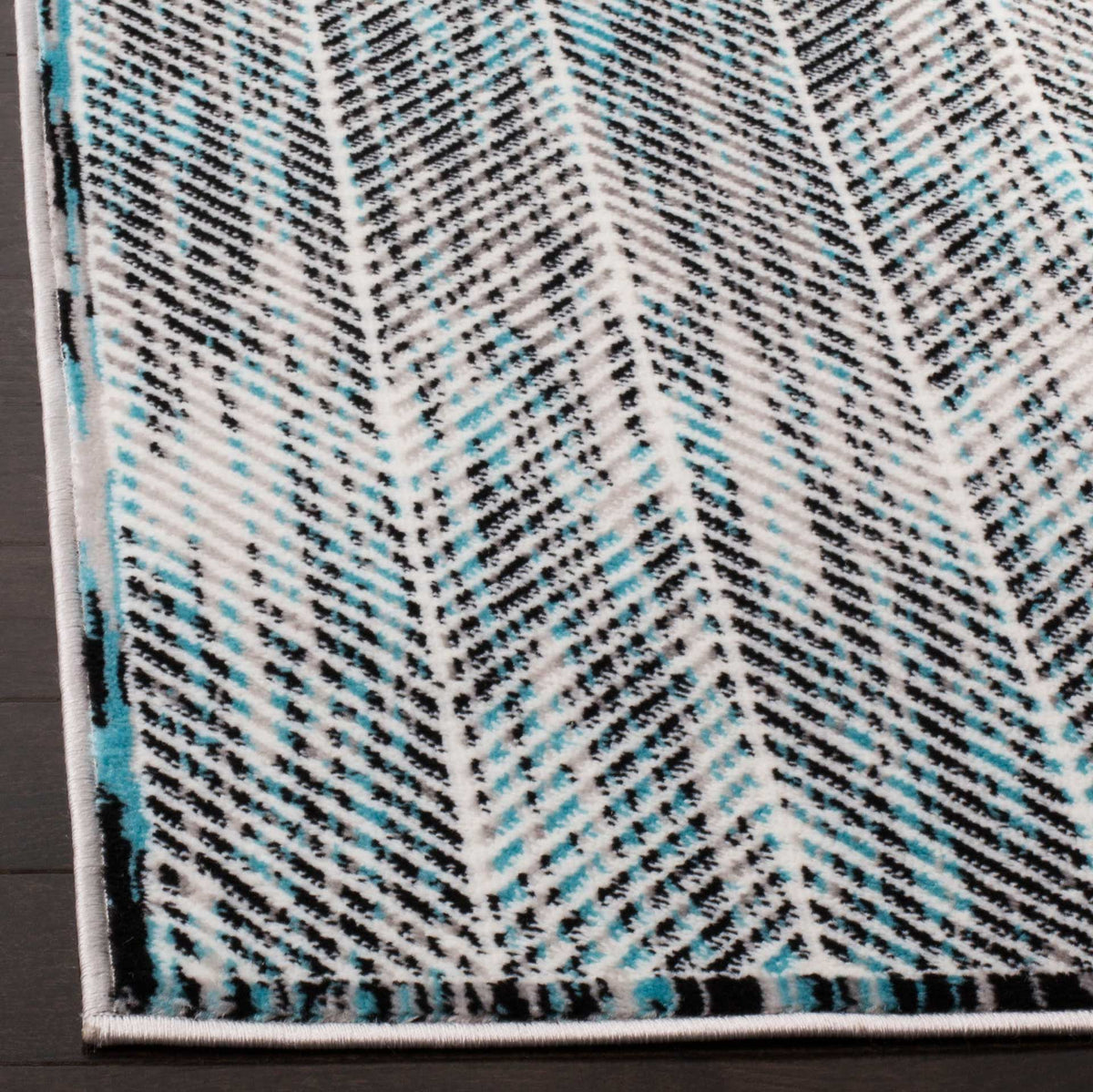 Blue, charcoal and ivory chevrons meet a neatly bound rug corner