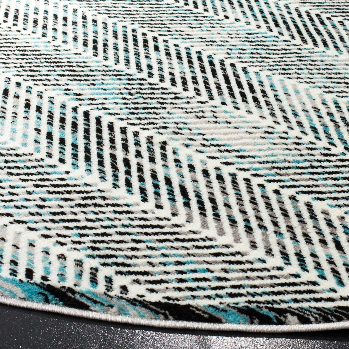 Blue and charcoal chevrons create layered texture along the bound rug edge