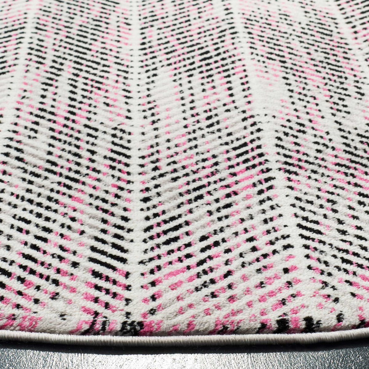 Pink and charcoal lines form crisp chevrons above the rug's bound edge