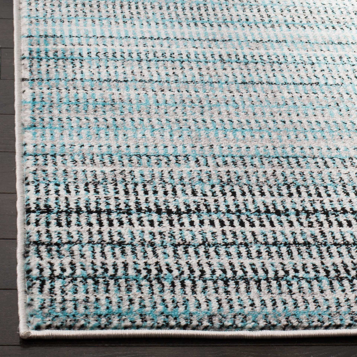 A neatly bound edge frames the rug's textured weave of blue, gray, and ivory stripes.