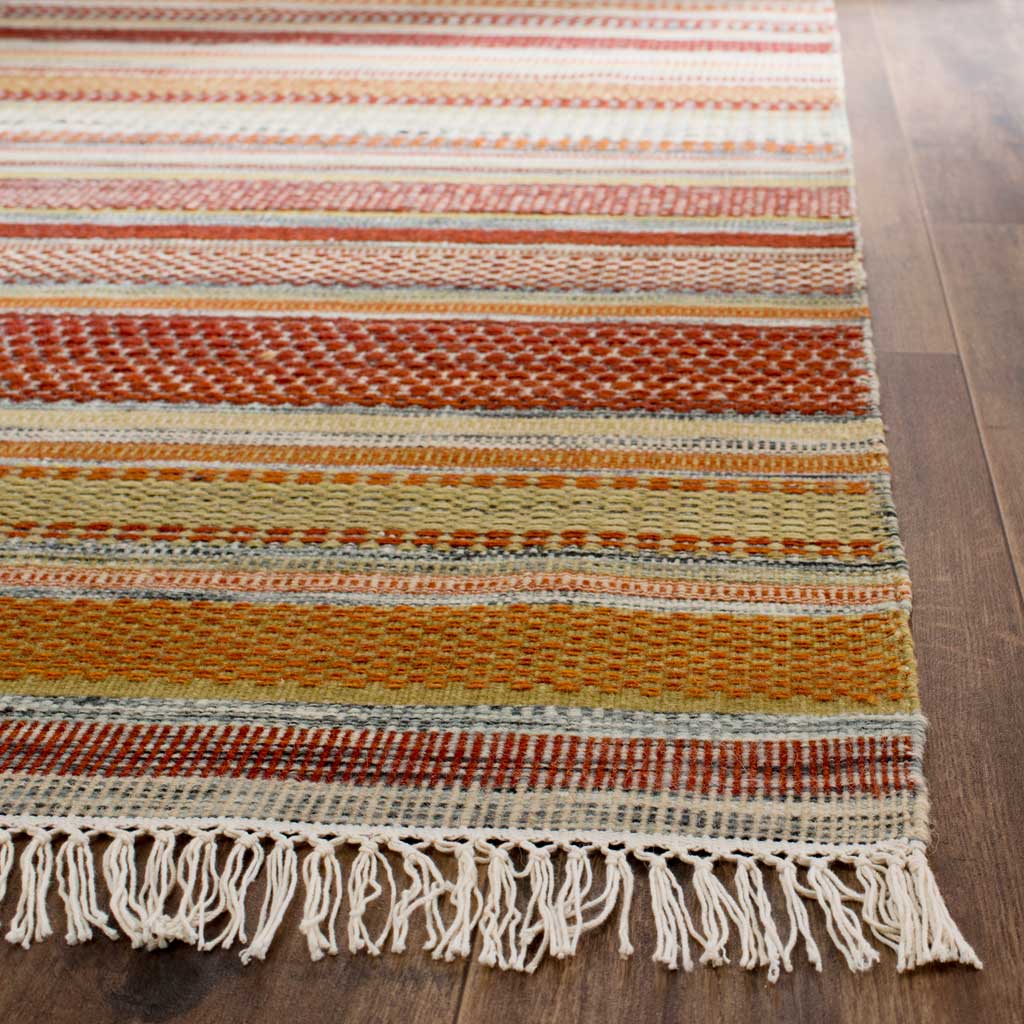 Knotted ivory fringe finishes a flatwoven rug with textured rust, coral, and beige stripes