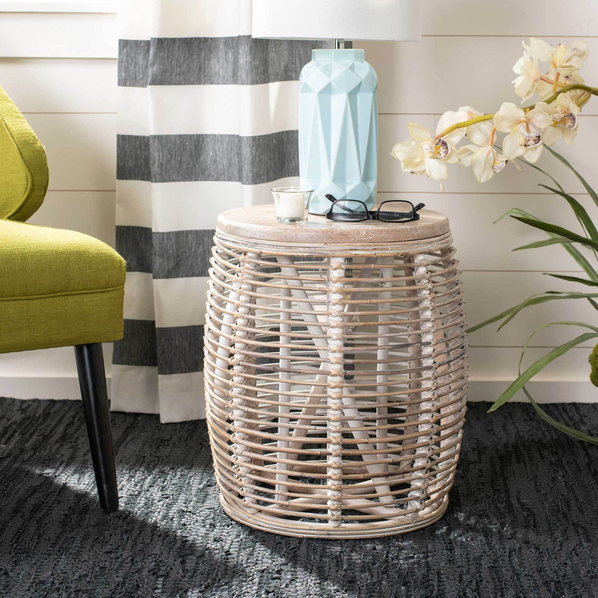 Gray-whitewashed woven stool serves as a side table with room for a lamp and a drink