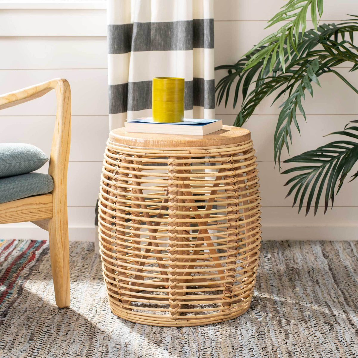 Natural golden-brown rattan stool doubles as a side table for books and a drink