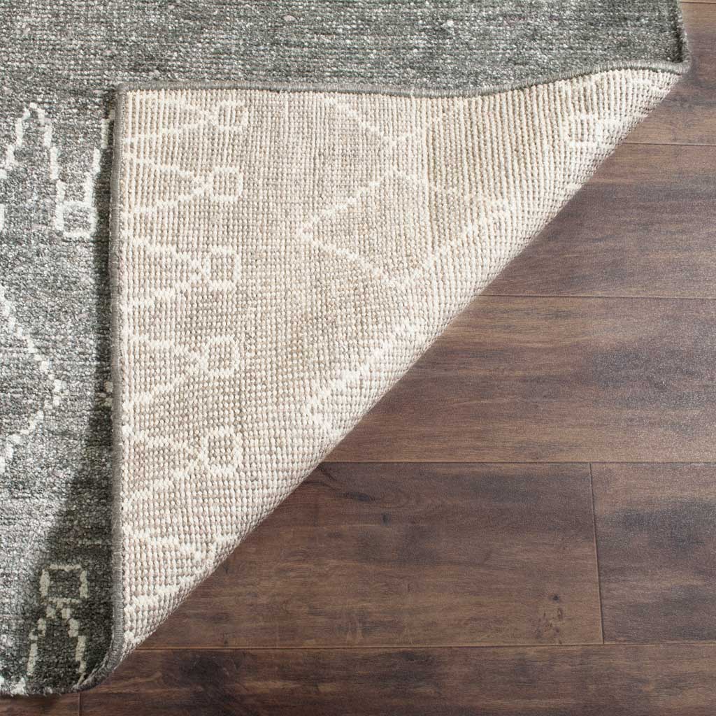 Folded corner reveals a light woven underside beneath the gray-and-ivory rug