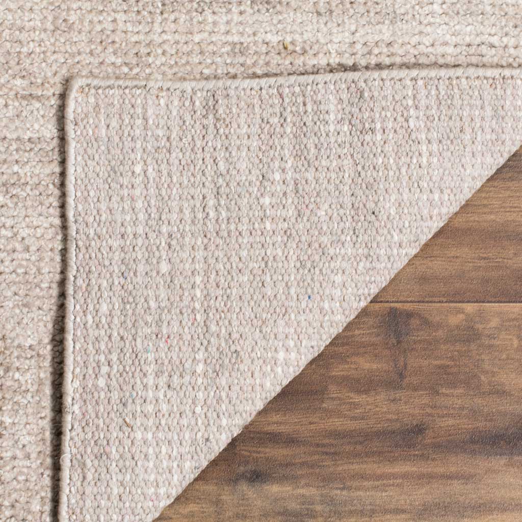 Folded corner displays the light woven backing of this pale gray rug
