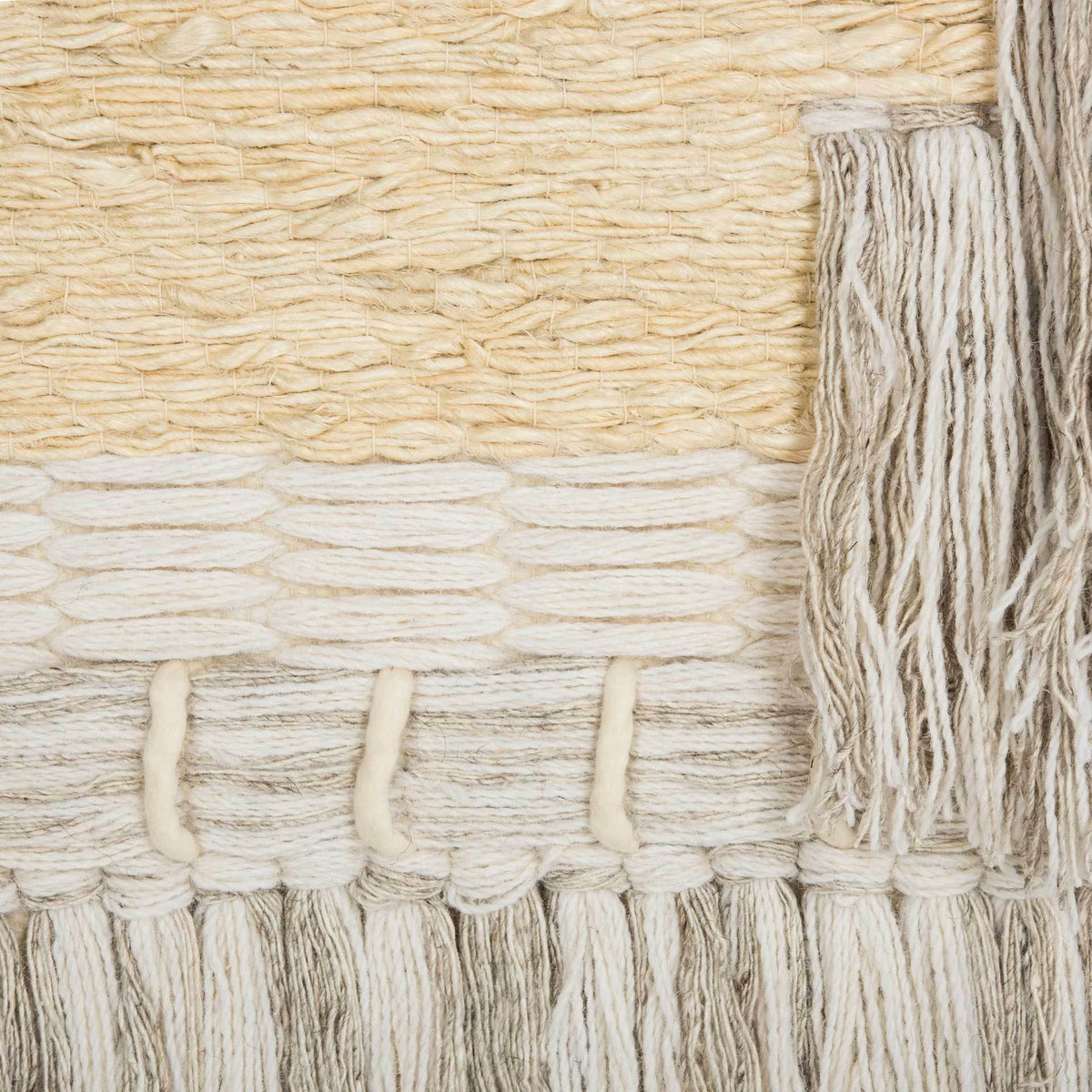Cream and sandy jute yarns form textured rows beside soft side fringe and tied tassels.