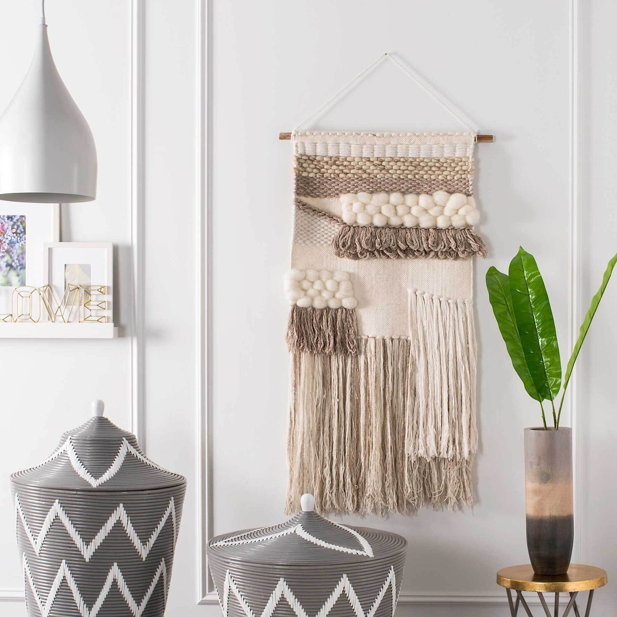 Cream tufting and two-tone fringe create a rich, asymmetrical finish on this neutral wall hanging.