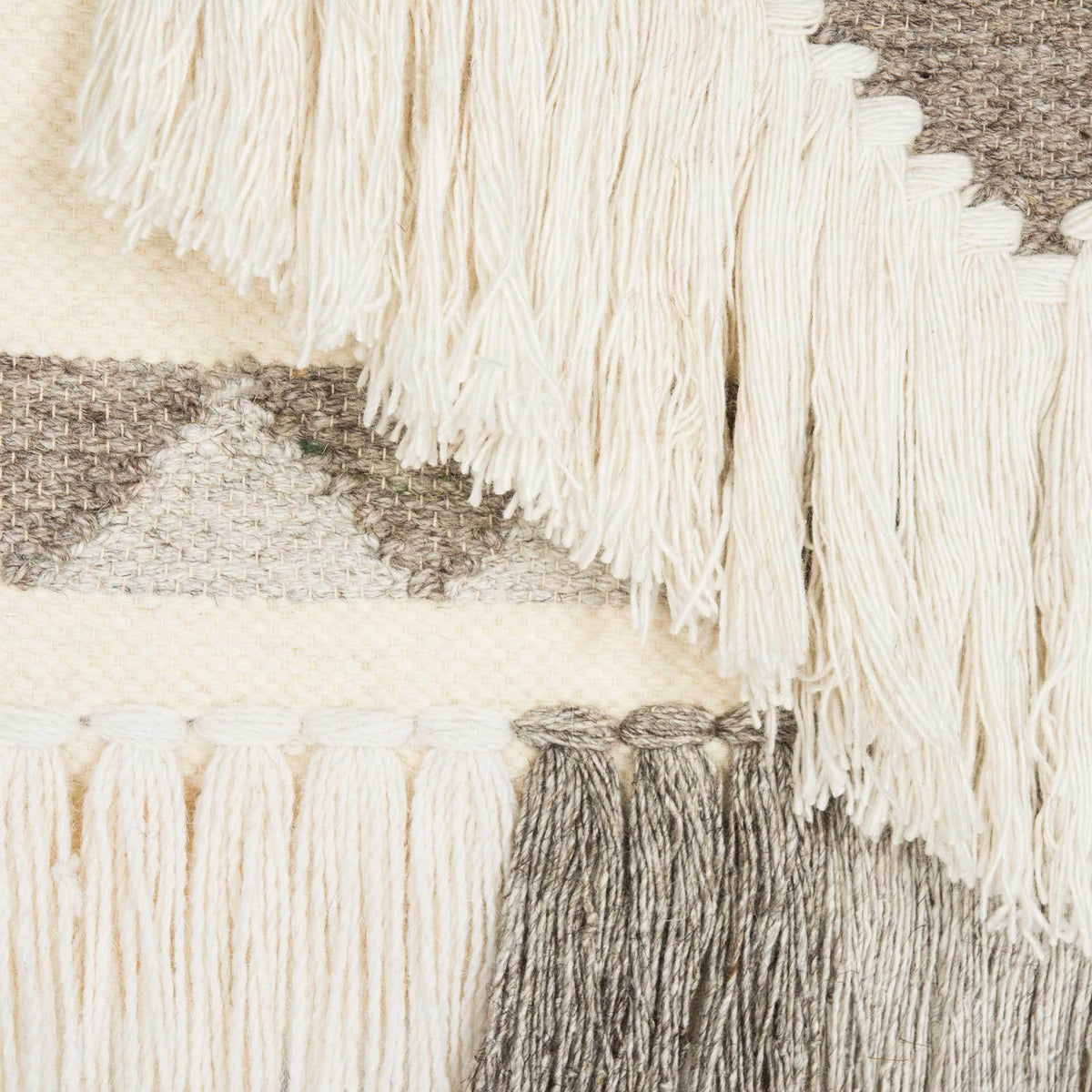 Soft ivory fringe outlines woven brown triangles above a row of deep taupe tassels.