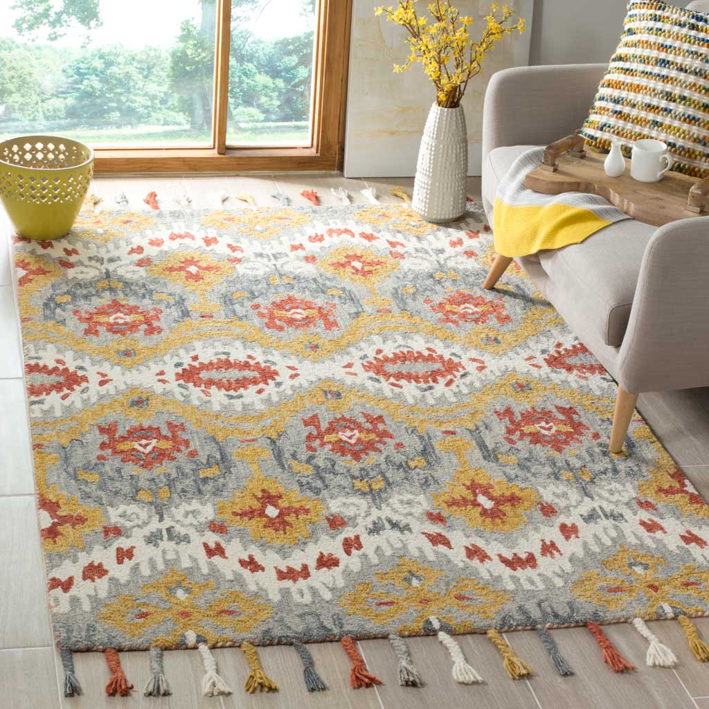 Gold and rust medallions enliven a gray and ivory wool rug with playful tassels beside a cozy sofa