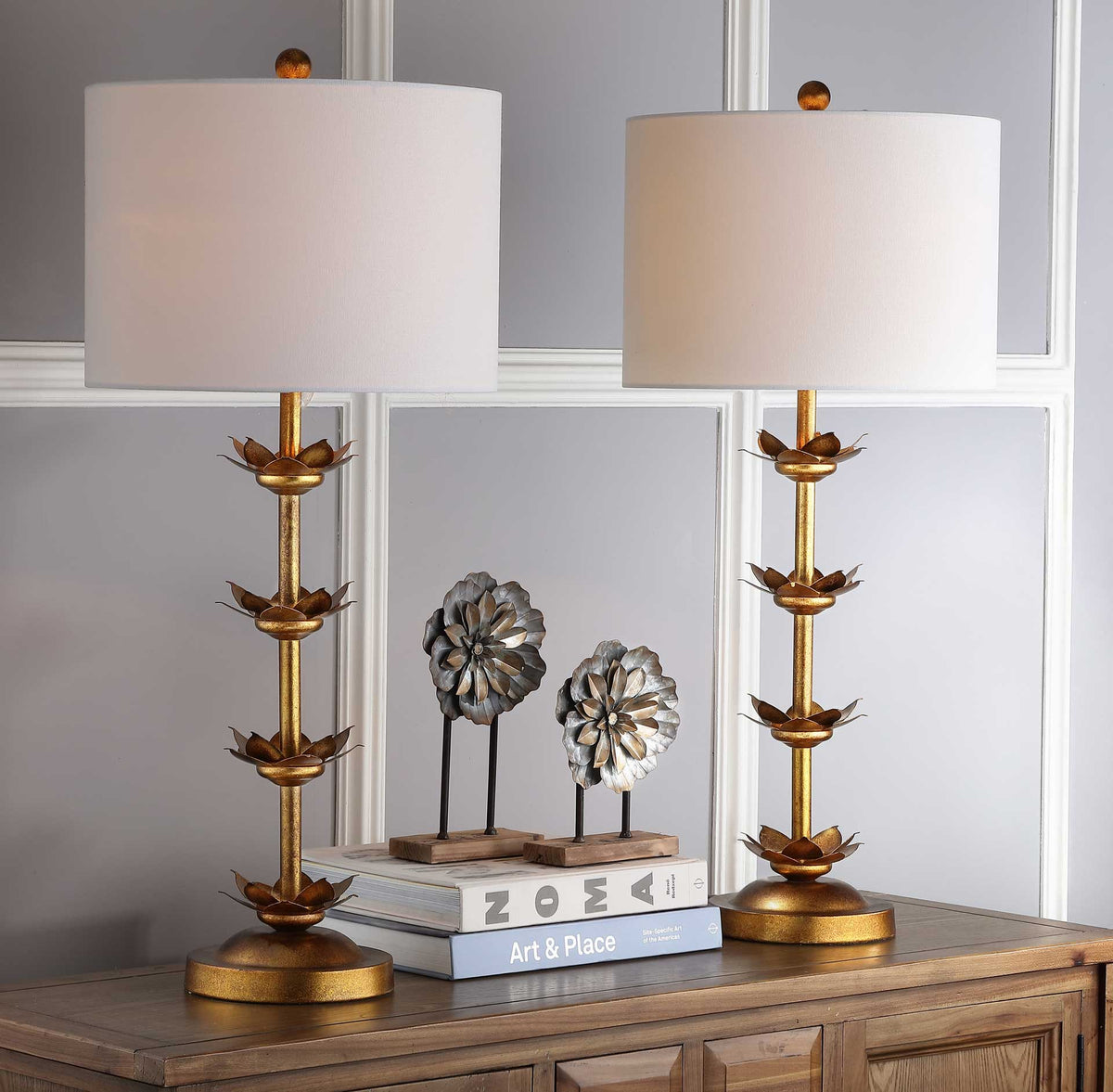 Two glowing table lamps pair soft white shades with gold stems and layered leaf details.