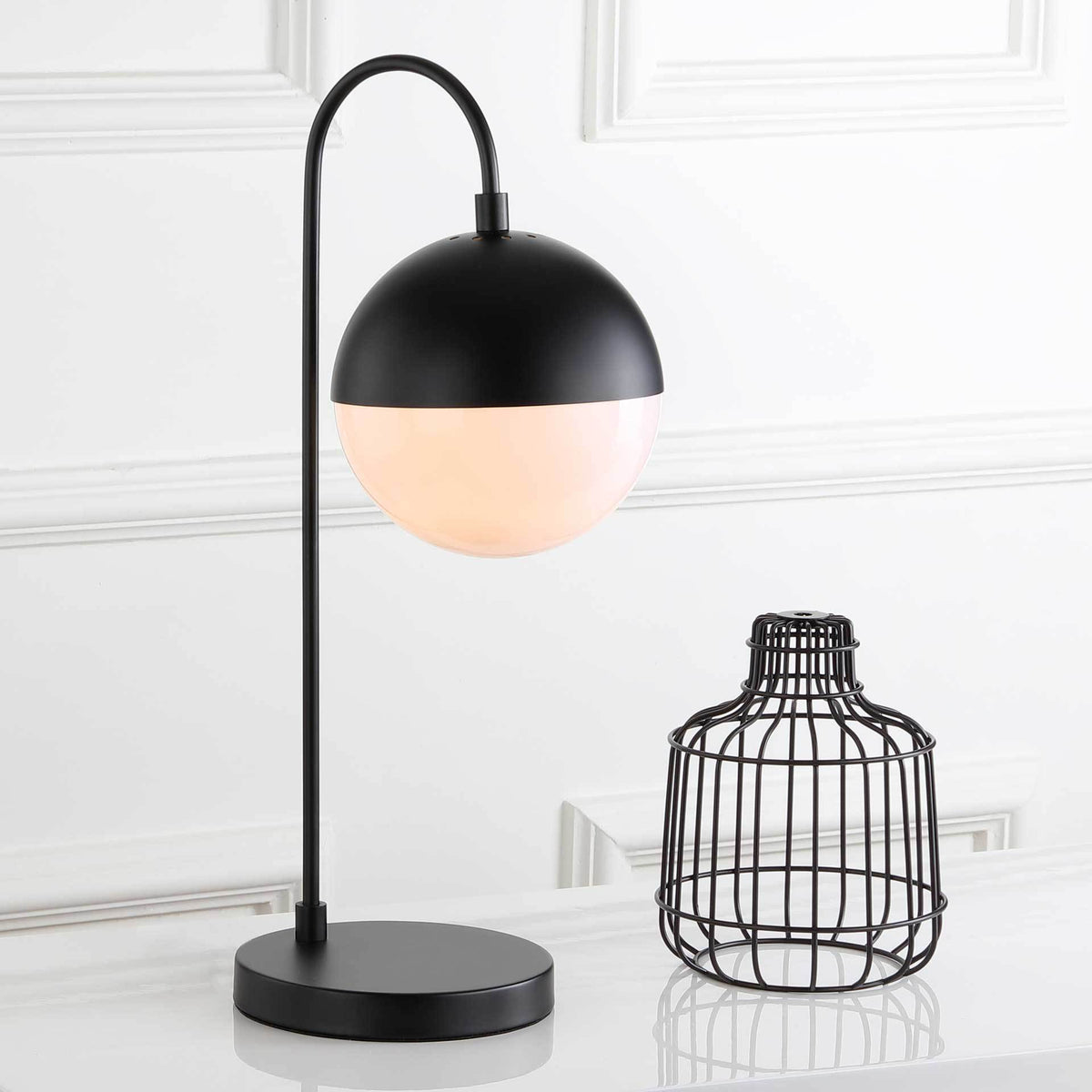 Soft, warm light shines through the globe beneath a black dome and curved stem.