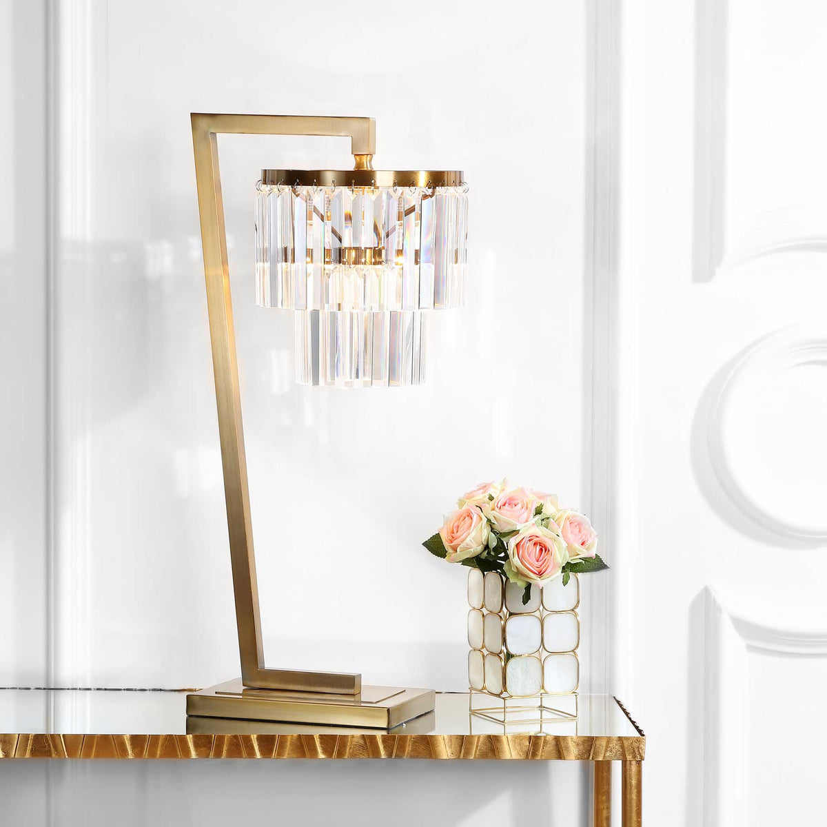 Illuminated crystal prisms bring a warm glow to this table lamp's striking gold-tone frame
