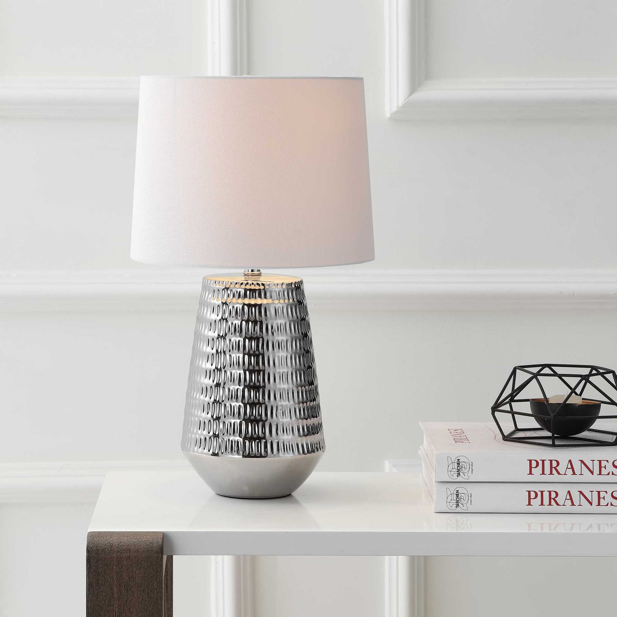 The softly glowing white shade complements the lamp's lustrous, textured silver base.