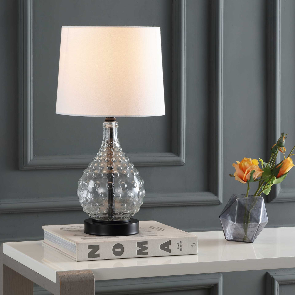 Warm light shines through a white fabric shade above a dimpled glass body