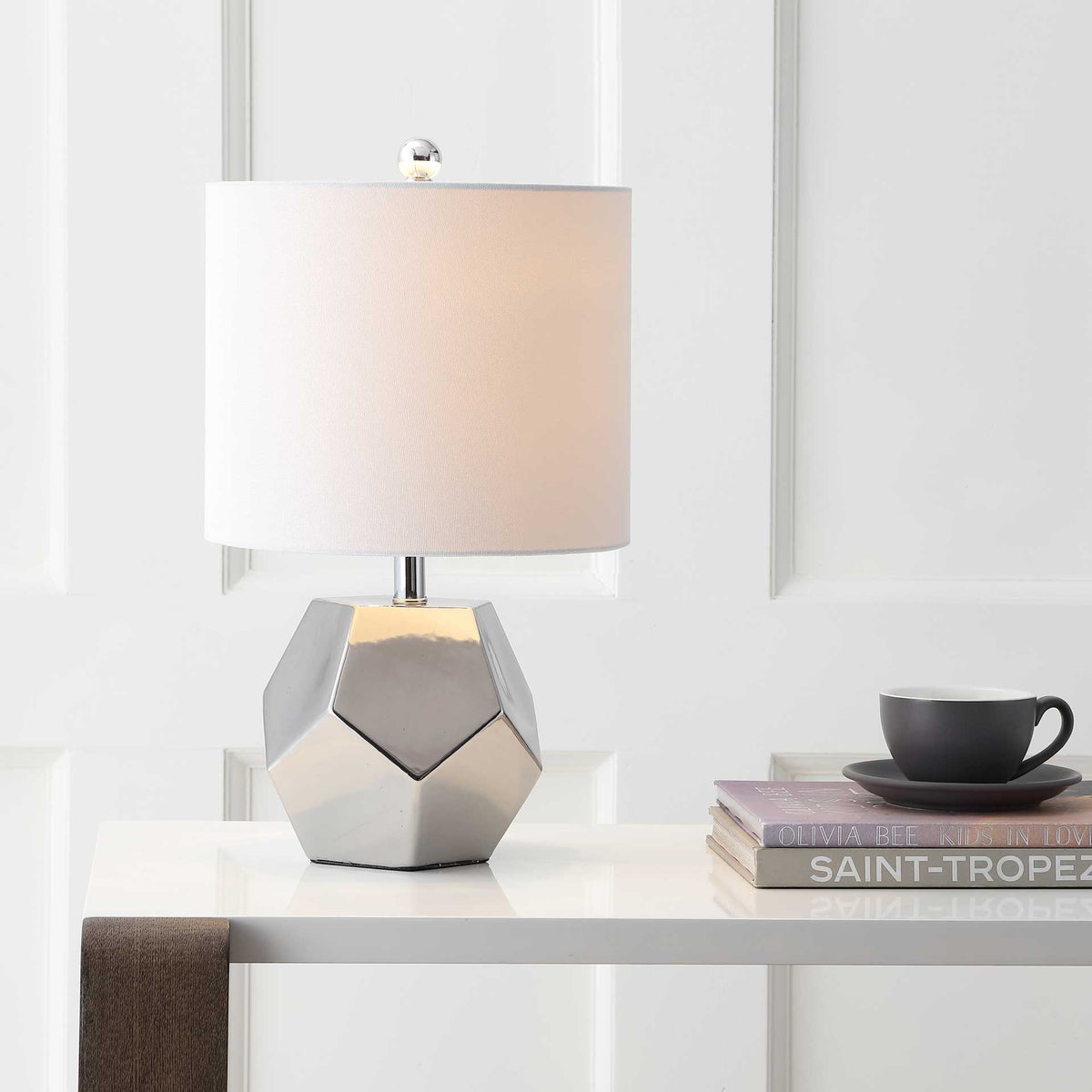 A softly lit white shade brings warmth to the lamp's reflective silver facets