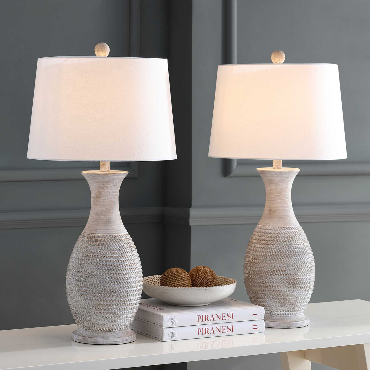 A pair of textured gray table lamps casts a warm glow through white fabric shades