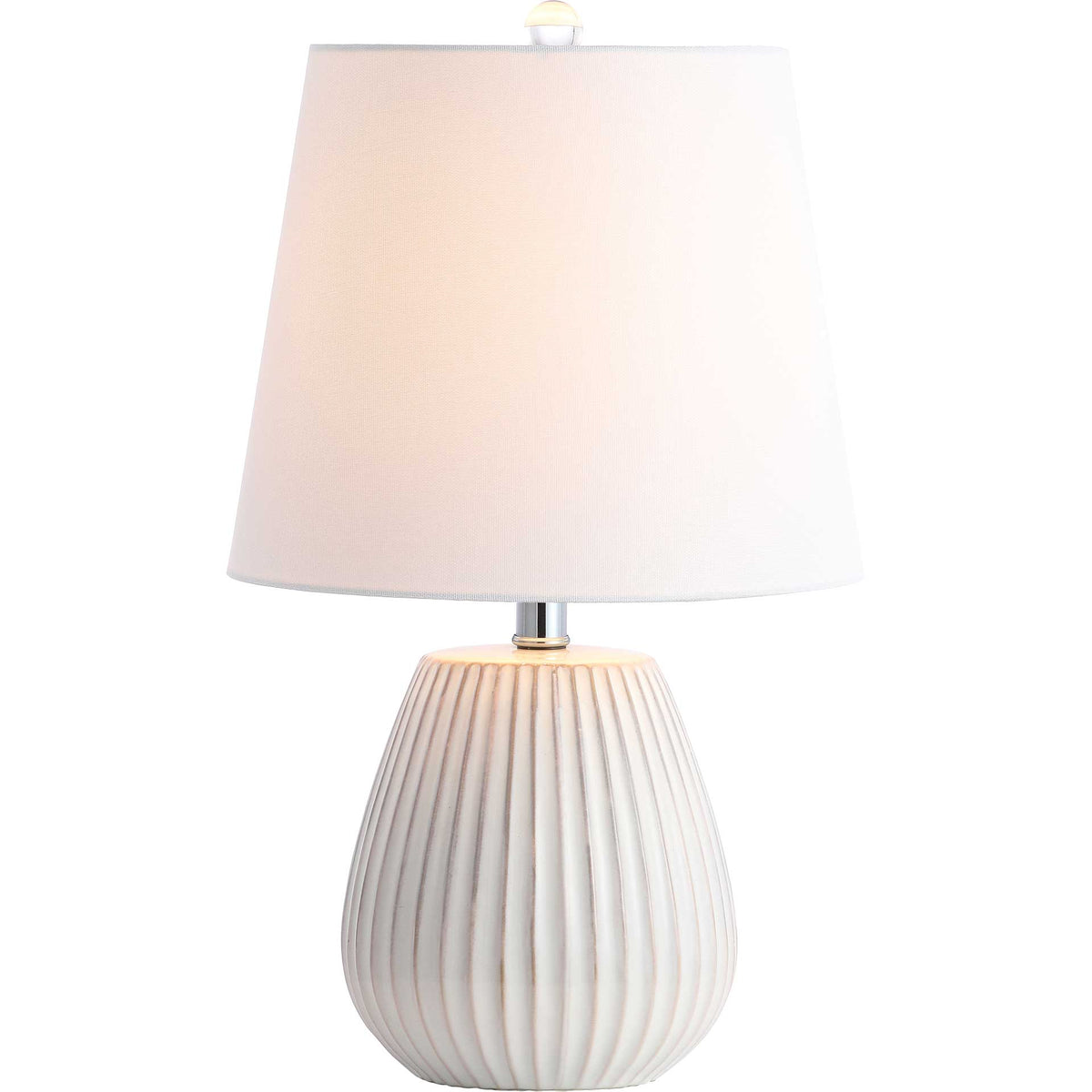 Warm light glows through a white fabric shade above a ribbed ceramic base