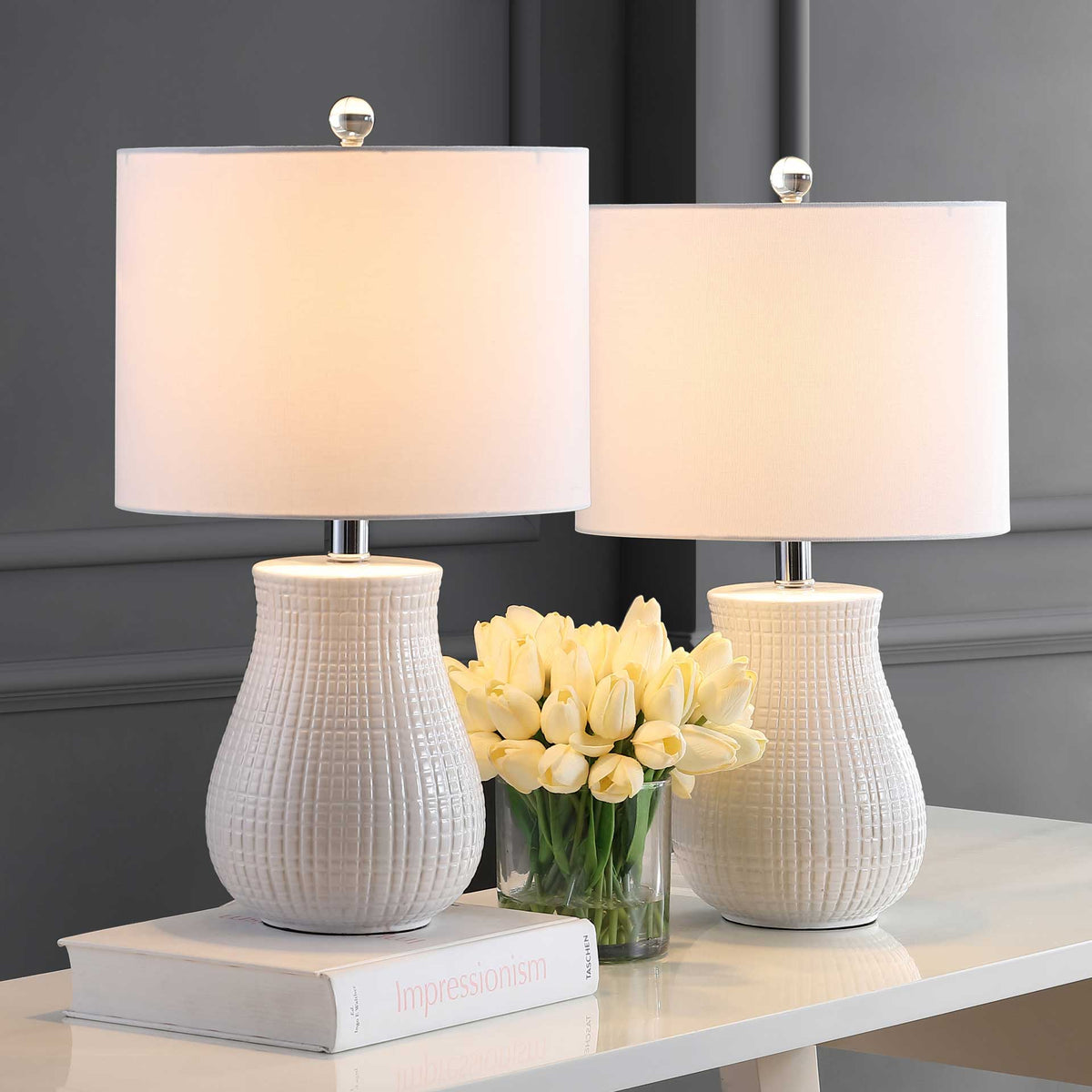 Two glowing drum shades cast warm light above matching white ceramic bases