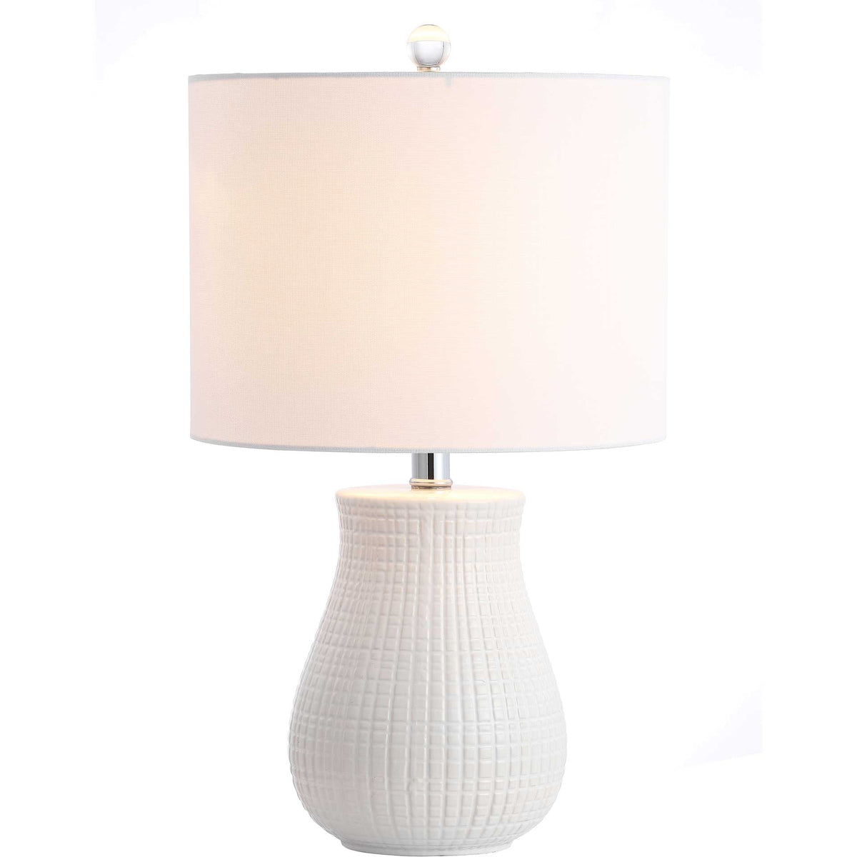 Warm light filters through a white drum shade above a sculptural ceramic base