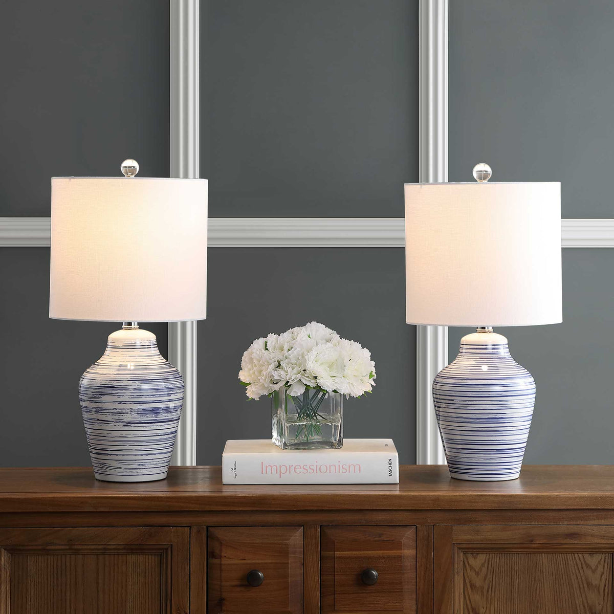 Two blue-and-white striped ceramic lamps glow warmly beneath white drum shades