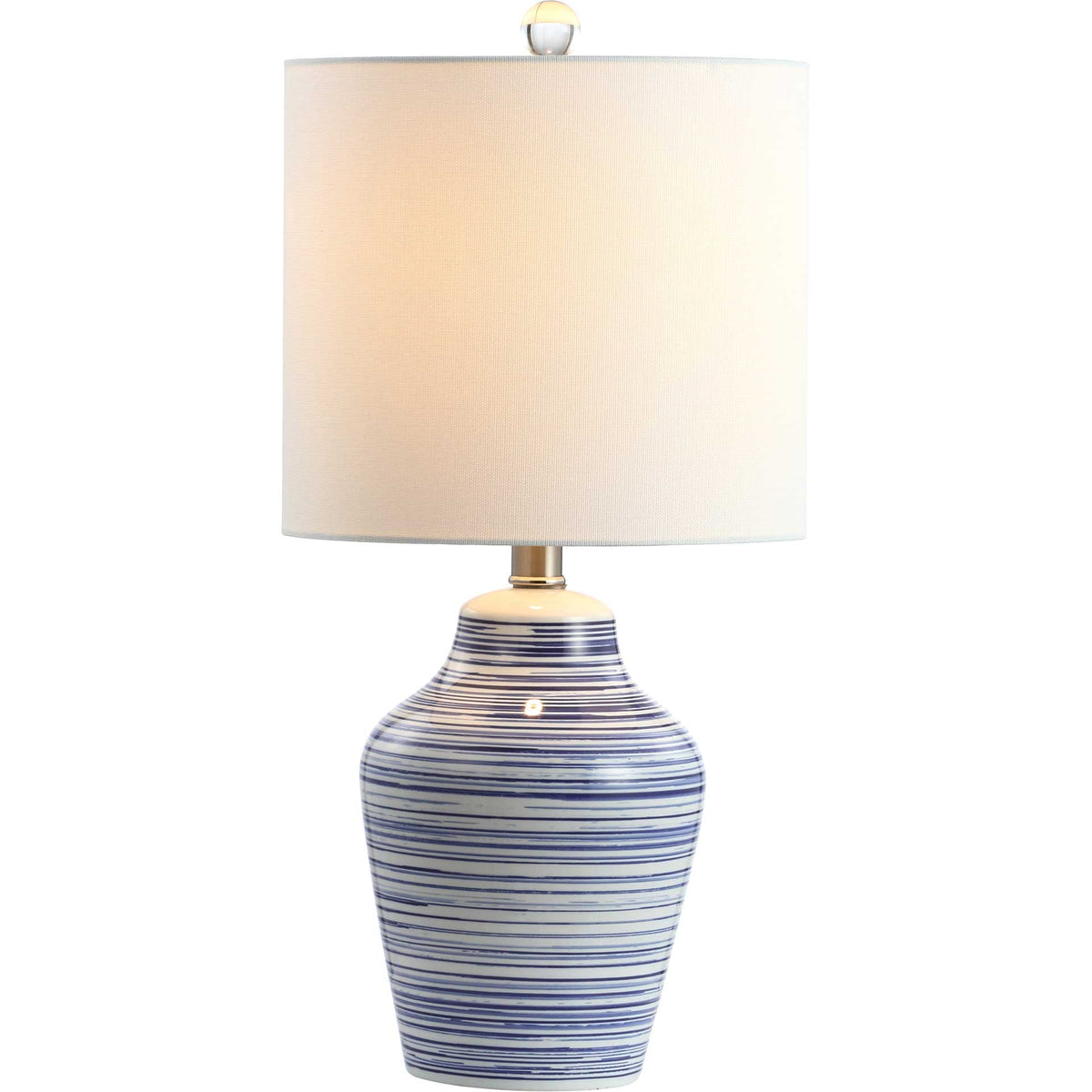 Warm light glows through the white drum shade above a blue-and-white striped ceramic base