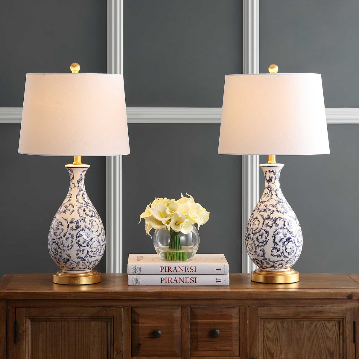 Two glowing white shades cast warm light above blue floral ceramic bases and gold-toned feet