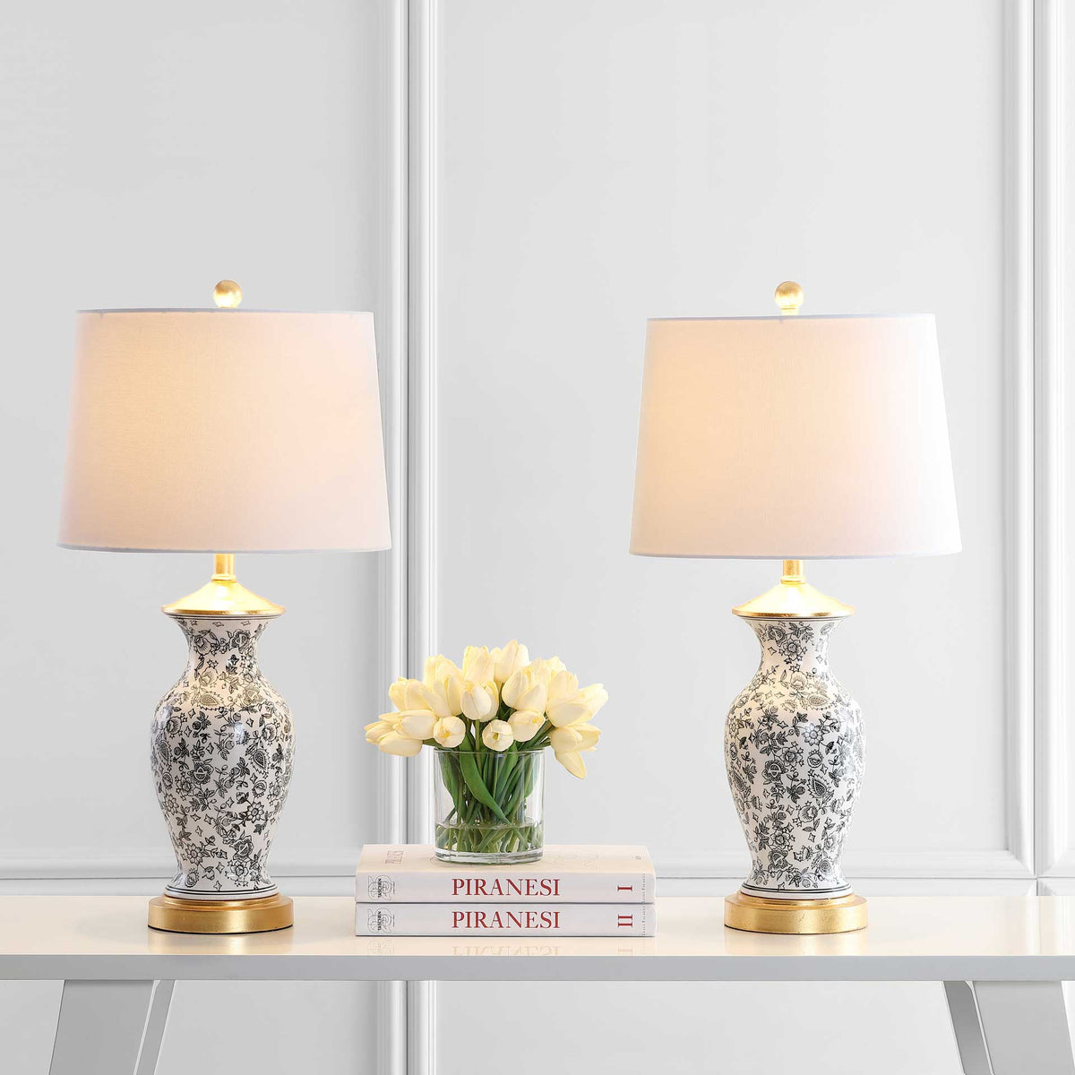A pair of floral ceramic lamps casts a warm glow through white shades above gold-trimmed bases