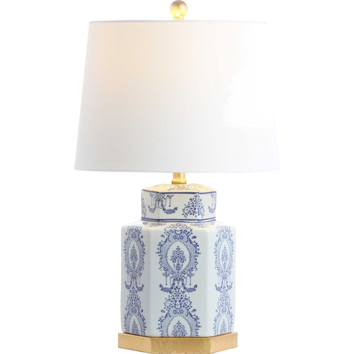 A blue-and-white ceramic lamp glows beneath its white fabric shade and rounded gold finial