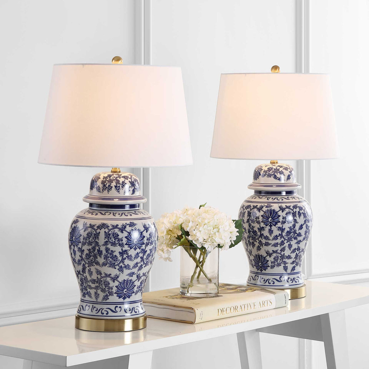 Two blue-and-white floral ceramic lamps cast a warm glow above a white console table