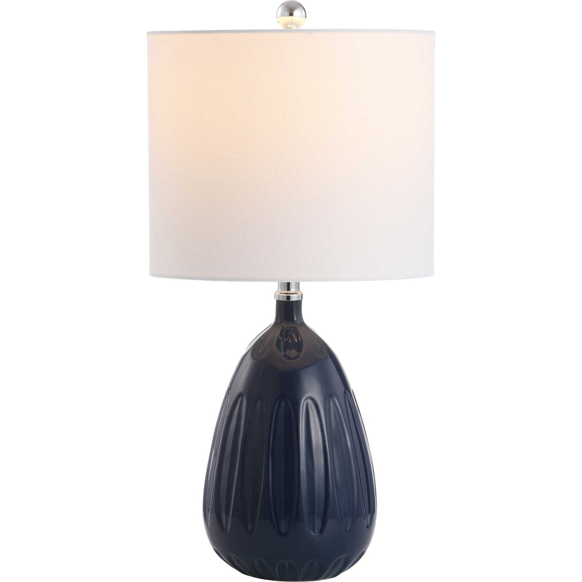 Warm light glows through a white drum shade above a sculpted navy ceramic base.