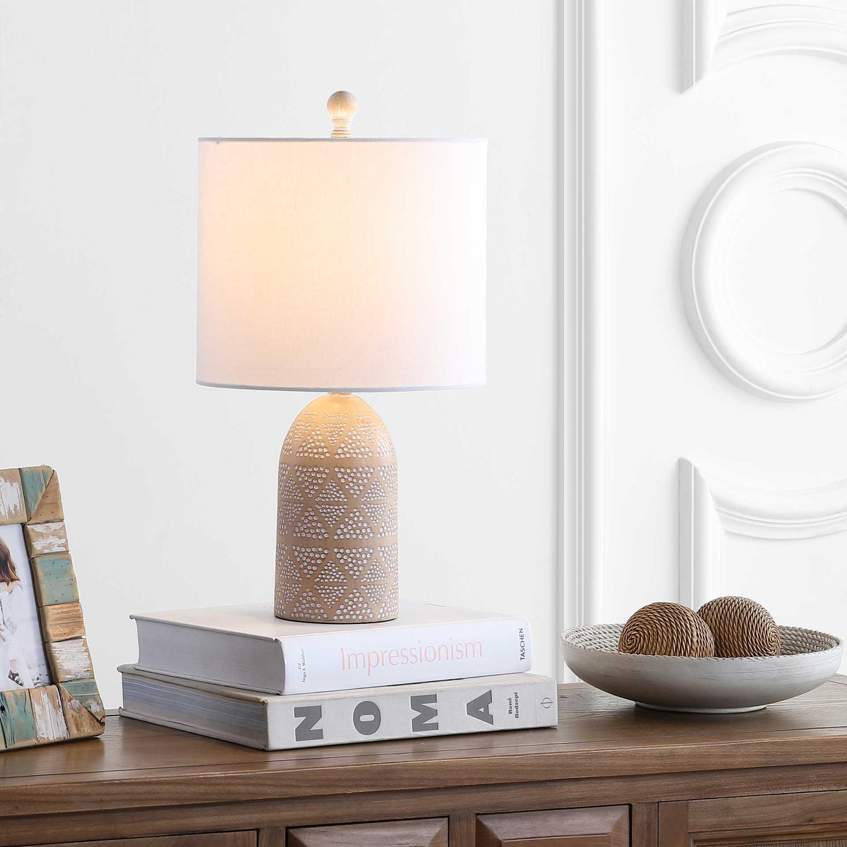 A softly glowing white shade and patterned sand-tone base create a welcoming tabletop accent