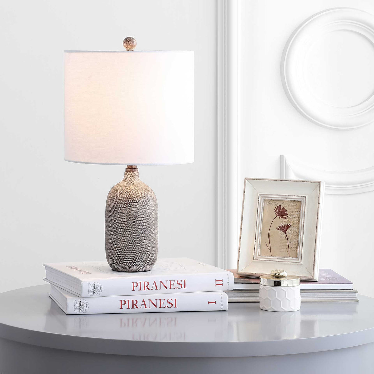 Soft light from the white drum shade brightens the accent table above a textured gray base.