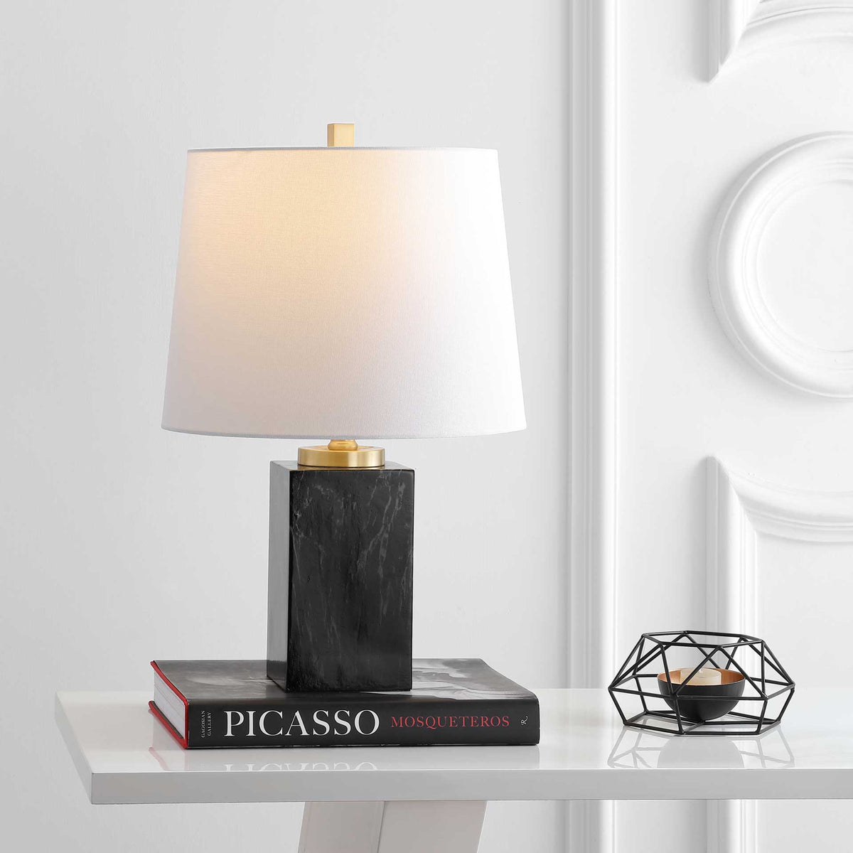A softly lit white shade brings a warm glow to the veined base and gold-finished details.