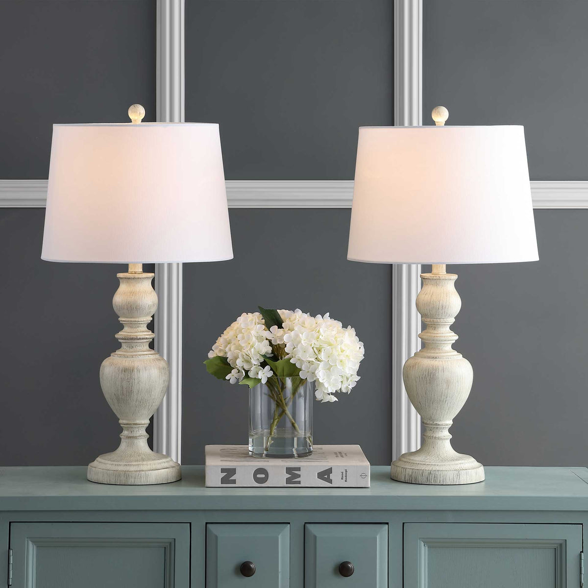 Two glowing white shades cast warm light above sculpted, whitewashed lamp bases.