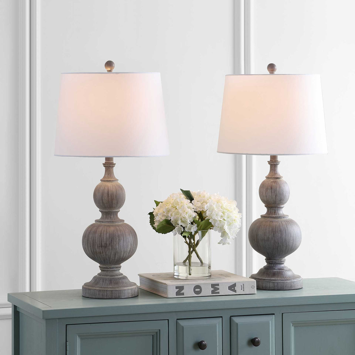 A pair of softly glowing white shades tops weathered faux wood bases.