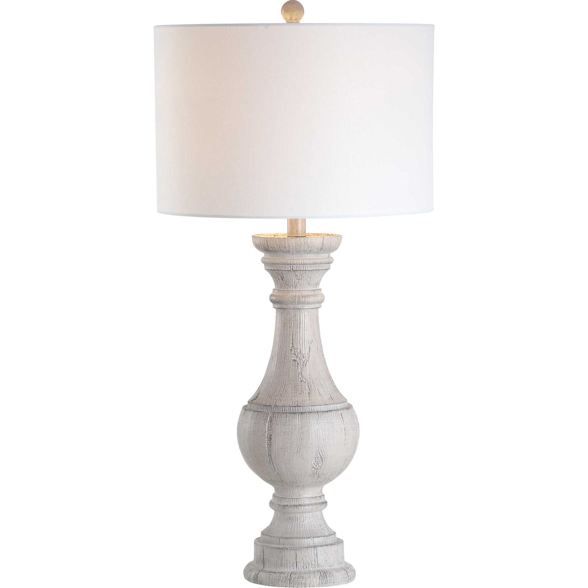 Warm light filters through a white fabric drum shade above a sculpted, whitewashed base.