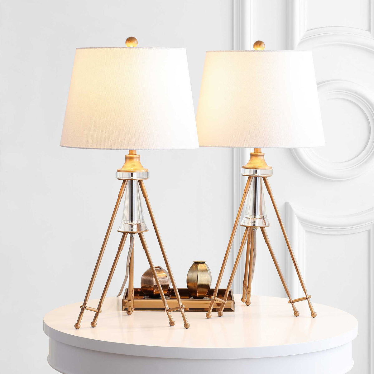 Two glowing off-white shades bring warm light to a pair of gold-tone tripod lamps with crystal accents.