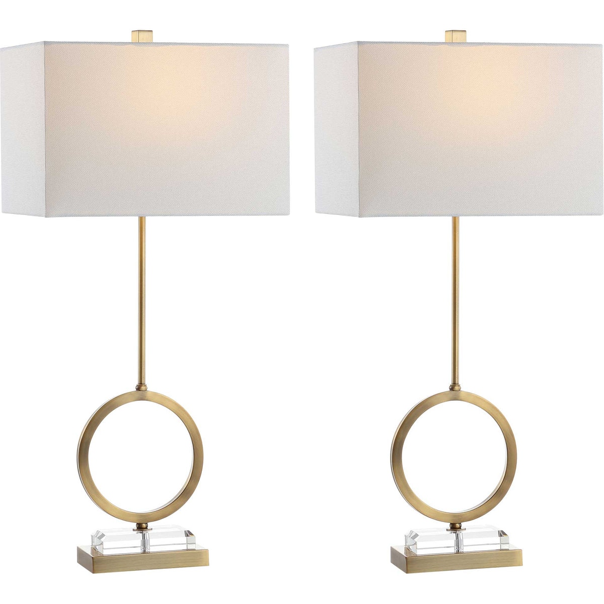 Matching brass ring lamps cast a warm glow through white shades above clear crystal bases