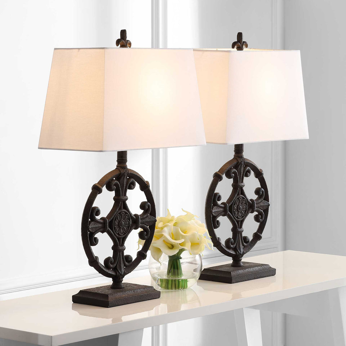A pair of black scrollwork table lamps casts a warm glow through white fabric shades