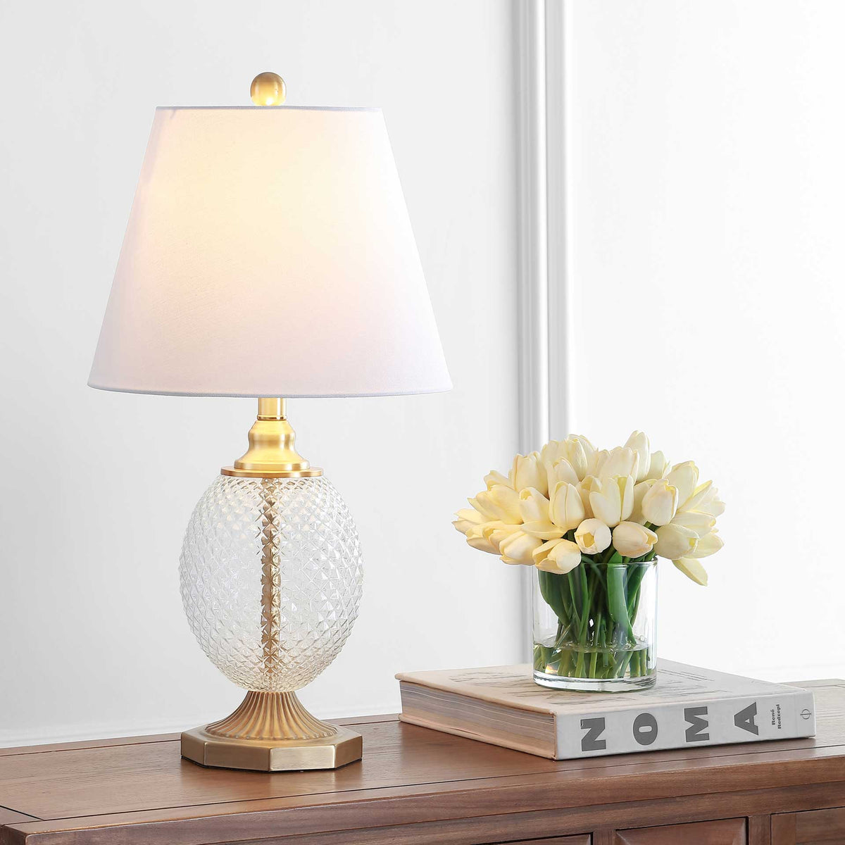 A softly glowing white shade pairs with clear textured glass and a fluted gold-tone base.