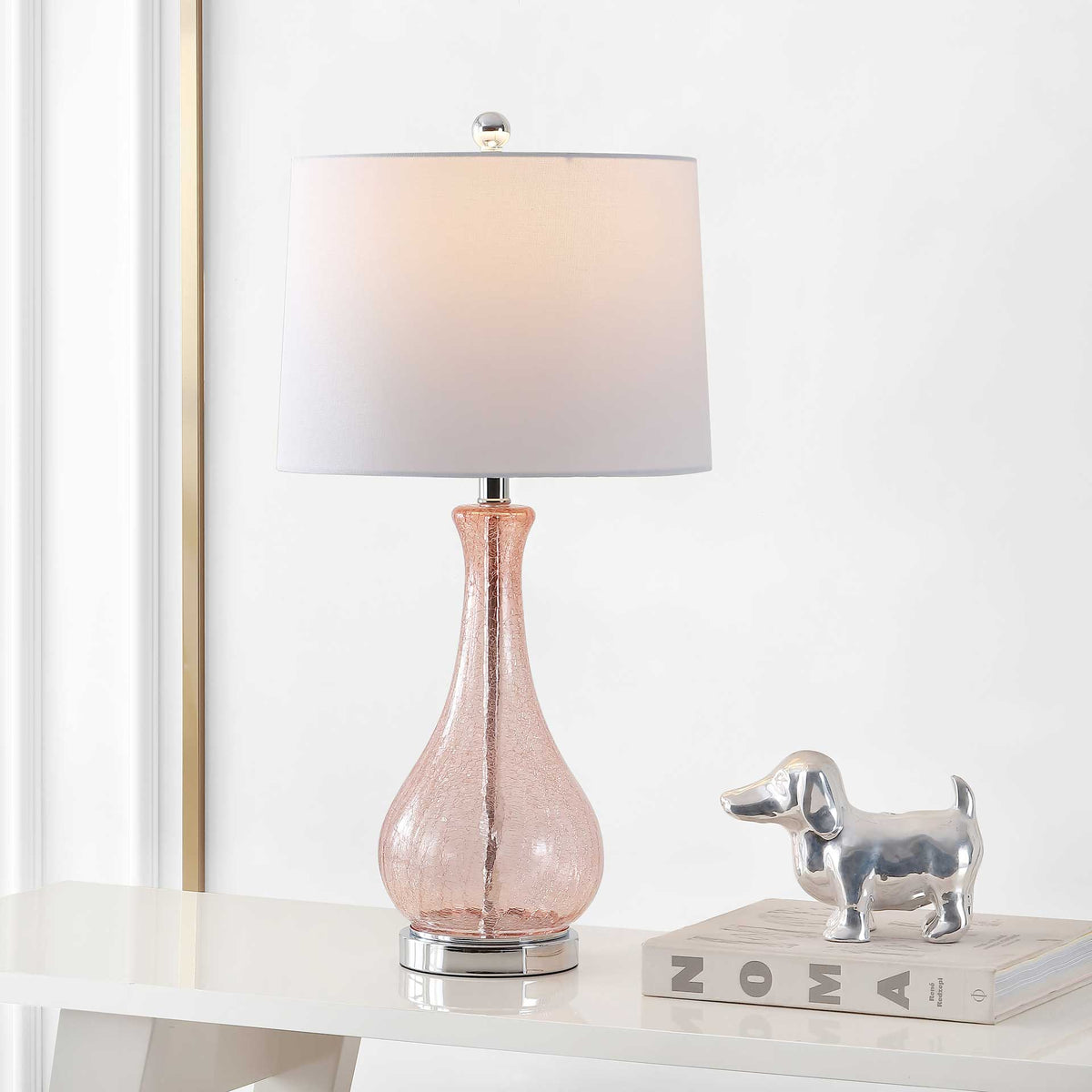 Warm light highlights the rosy glass base and casts a welcoming glow through the white shade