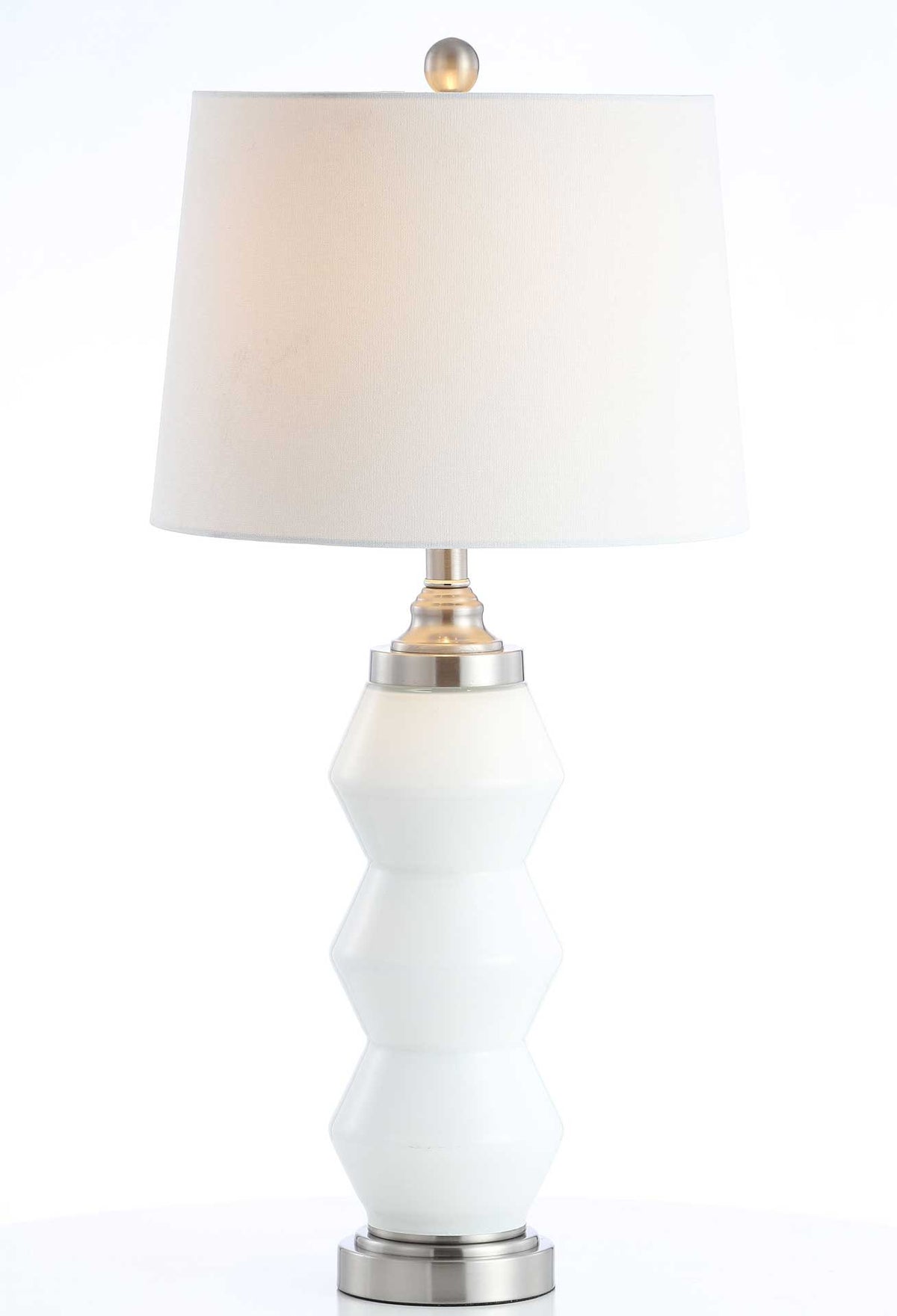 Warm light glows through the white shade above a faceted glass base with silver-tone trim