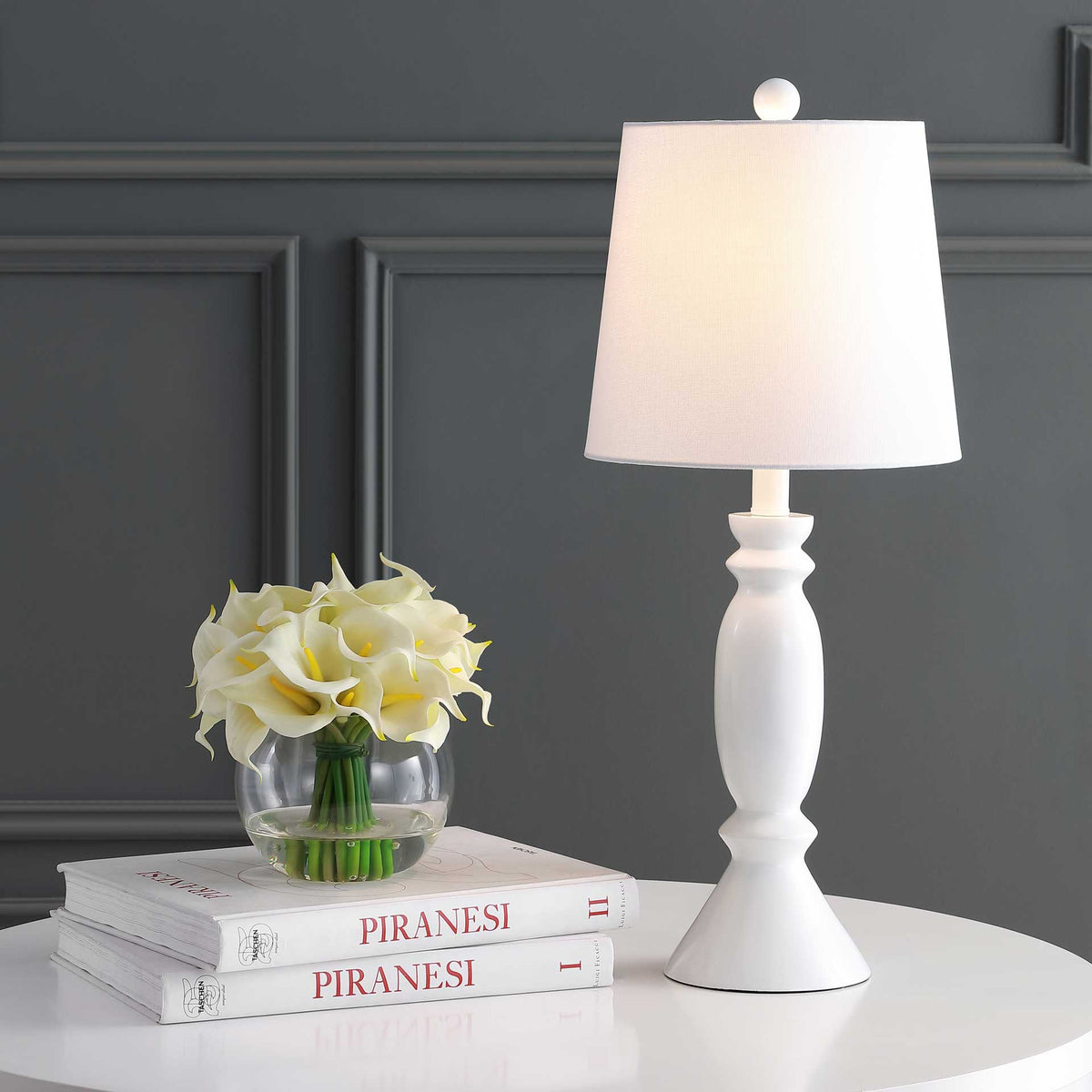 Warm light glows through the fabric shade above an elegantly curved white base