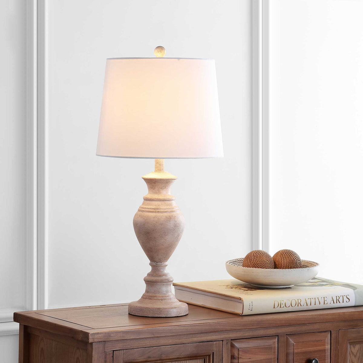 A glowing white shade crowns a weathered brown urn base, adding warmth to the room.