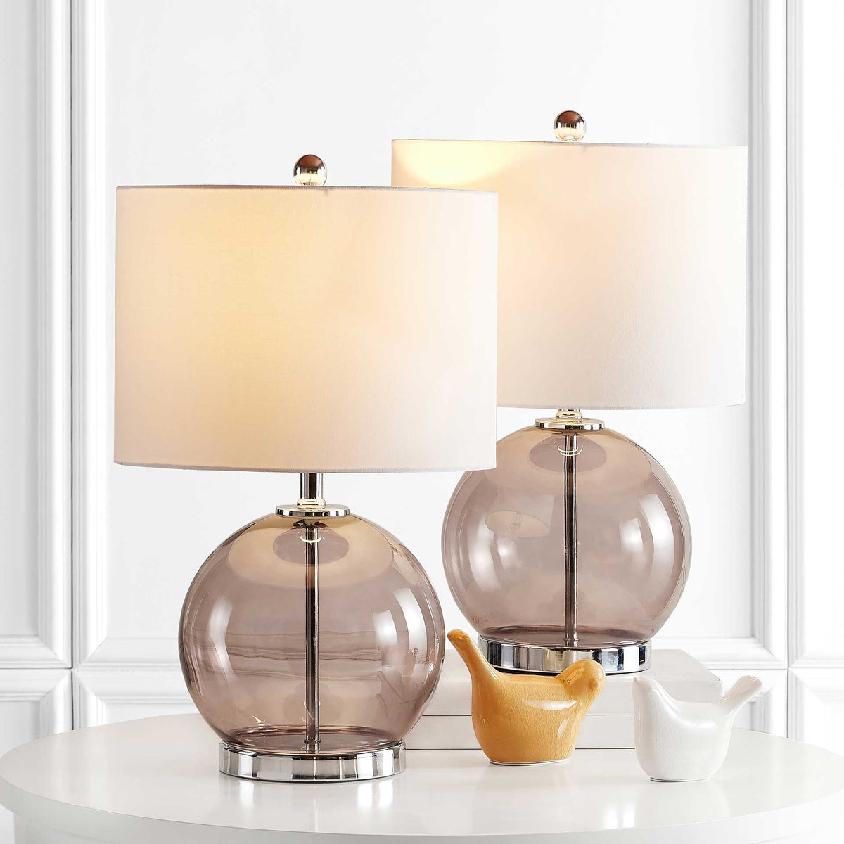 Warmly lit white shades brighten a pair of gray glass globe lamps with chrome bases
